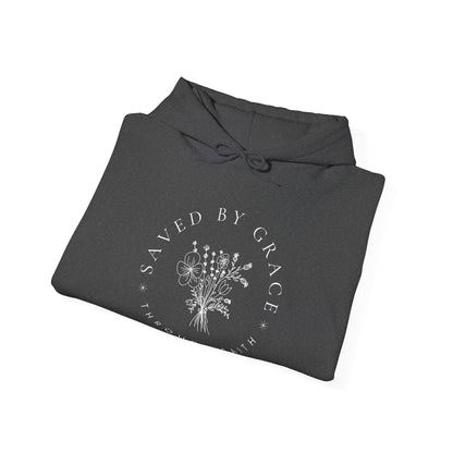 Folded dark gray hoodie with 'Saved by Grace' text and floral design on a white background